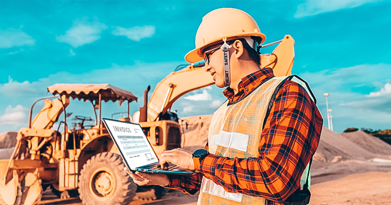 A heavy equipment operator managing equipment rental on the laptop using software