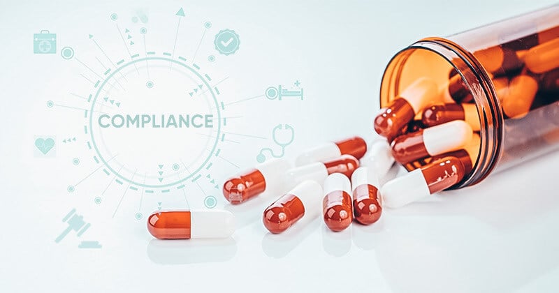 A vial of tablets spread across the table with an inlay text of 'Compliance'