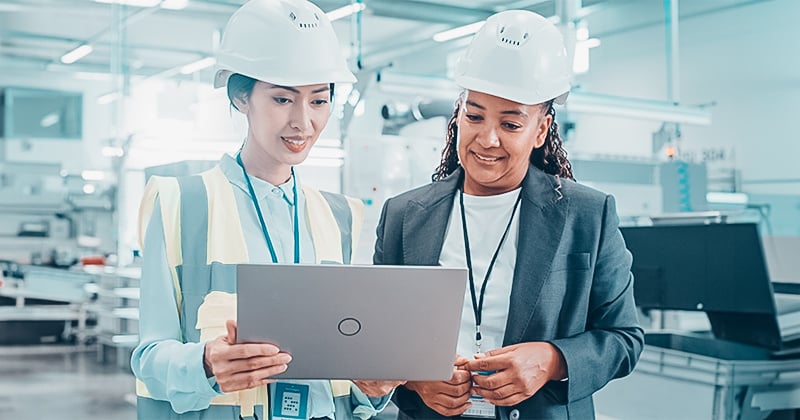 Two manufacturing employees working on a laptop