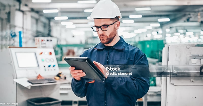 A manufacturer working on a hand-held device in a factory